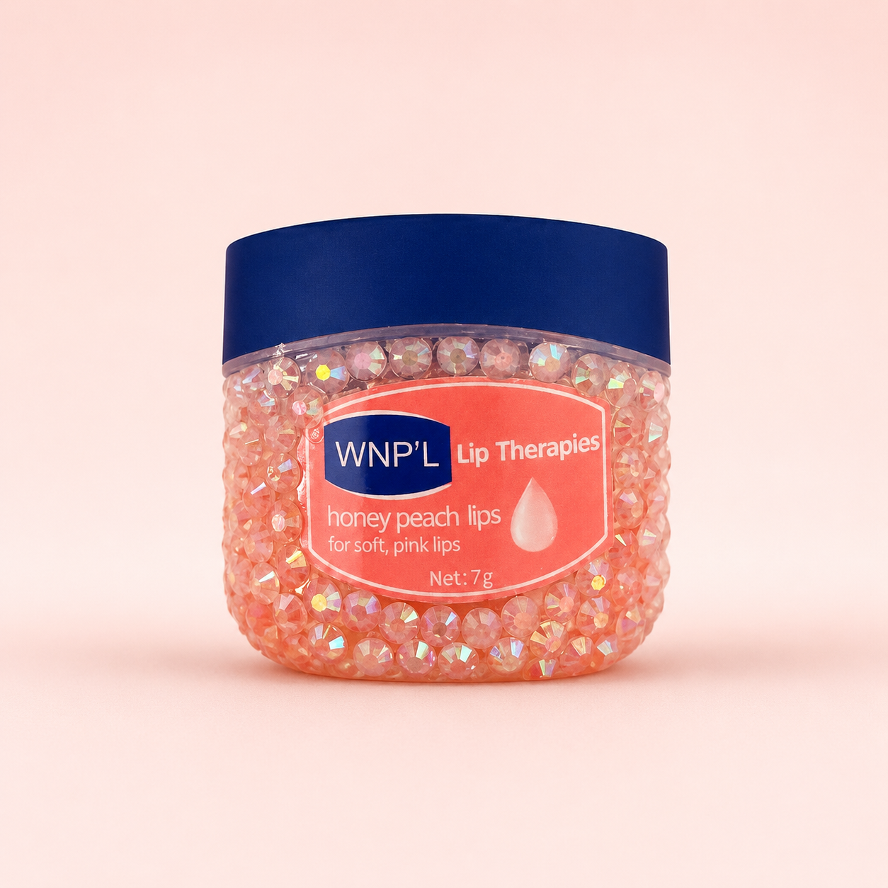 Small lip therapy jar covered in peach rhinestones with a navy lid